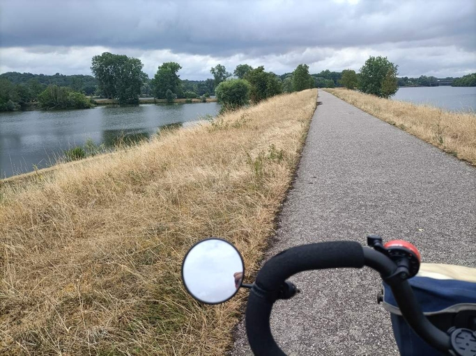 en arrivant à Nancy une piste cyclable avec un fleuve d'un côté, un étang de l'autre. Devant un bout de guidon de velo