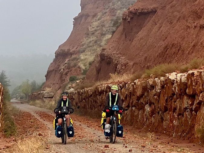 2 cyclistes, sur des vélos chargés, dans un chemin encaissé